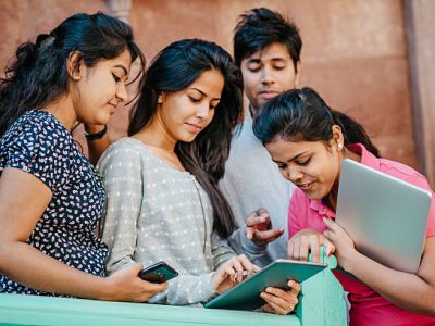 Pretty Smiling Young Indian Students with Laptop and tablet computer Looking at Camera